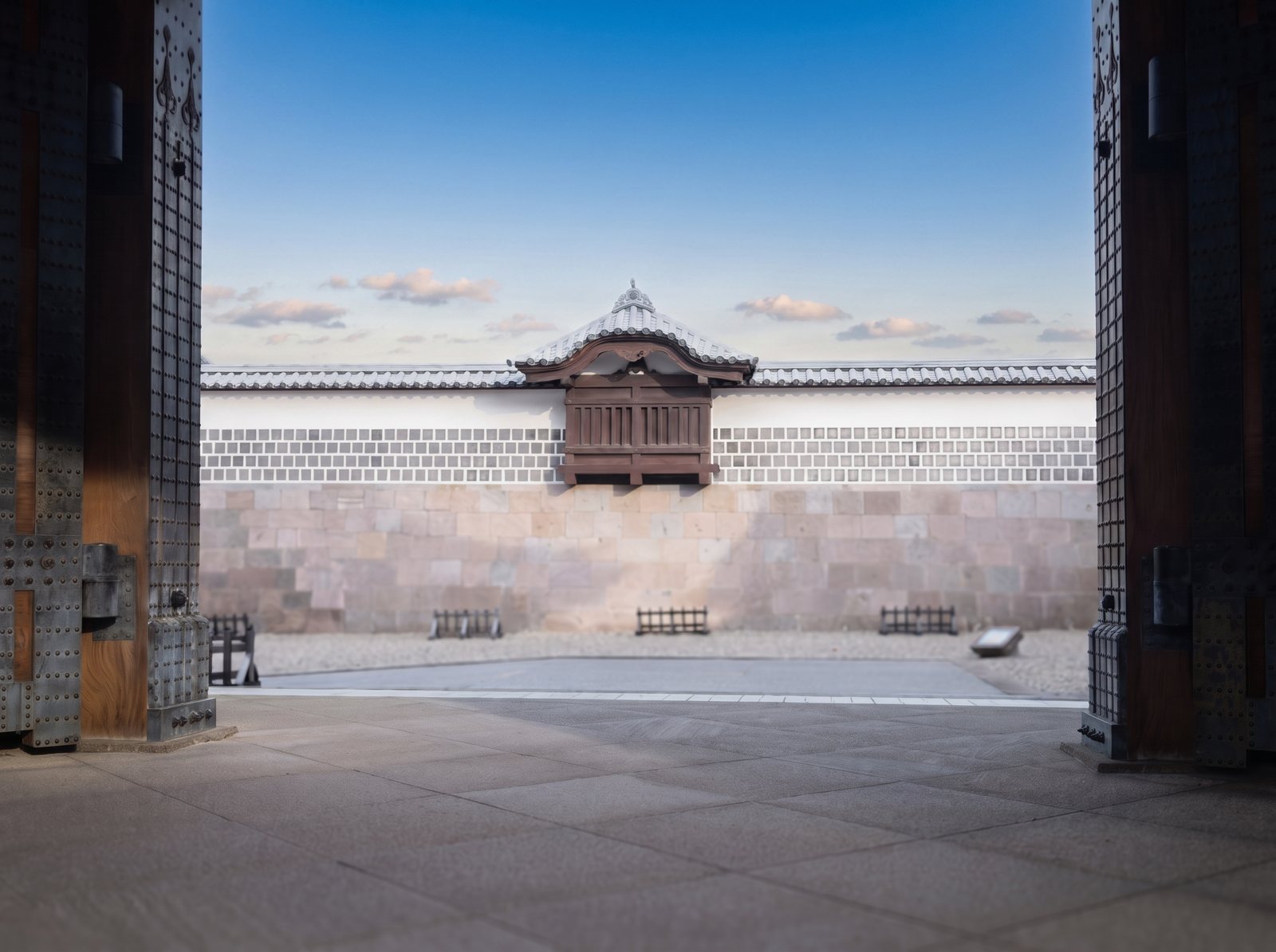 View through a heavy wooden castle gate to a white castle wall under blue sky