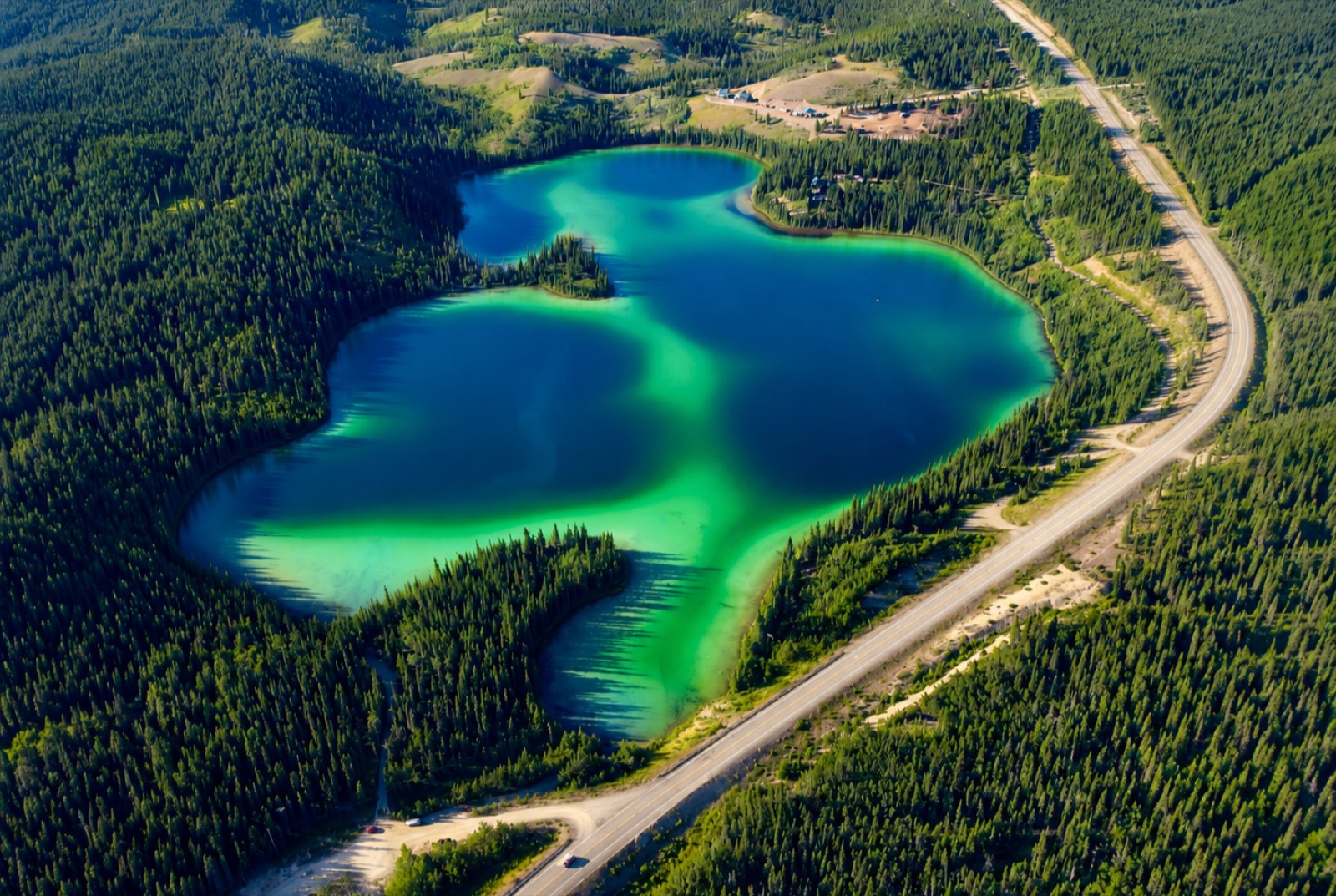 Two turquoise lakes ringed by boreal forest, seen from the air